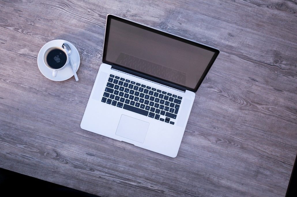 Laptop, daneben eine Kaffeetasse.